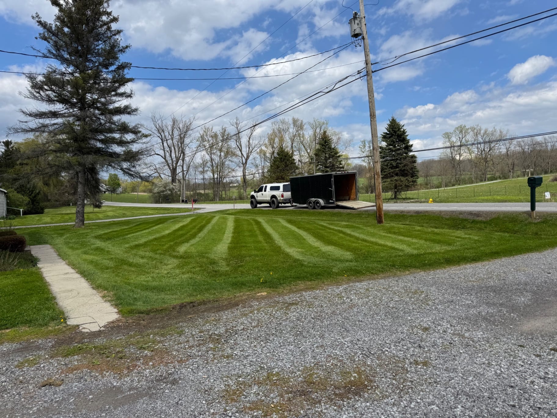 Freshly striped front lawn with work trailer parked along roadside