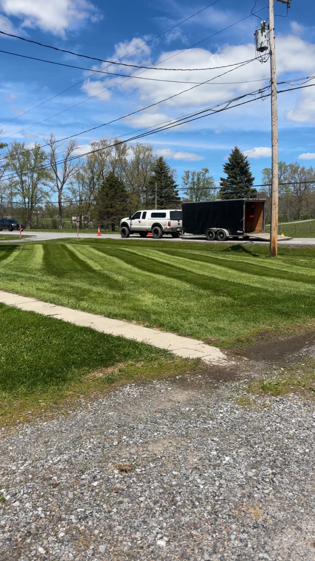Freshly striped lawn with truck and enclosed trailer at curbside