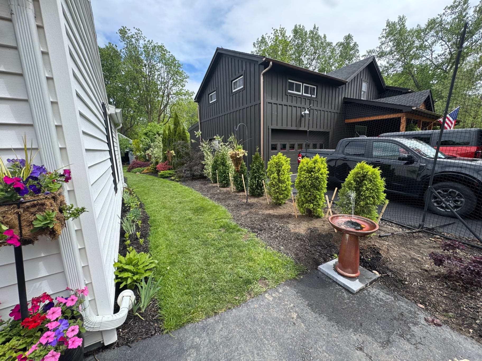 Fresh landscape bed with shrubs and flowers beside driveway